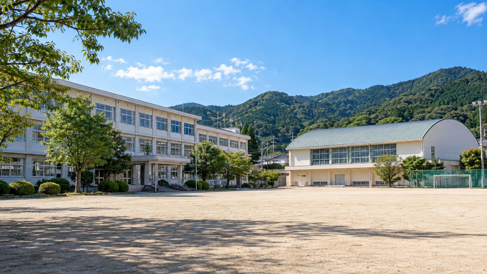 山を背にした校舎と体育館、広い校庭