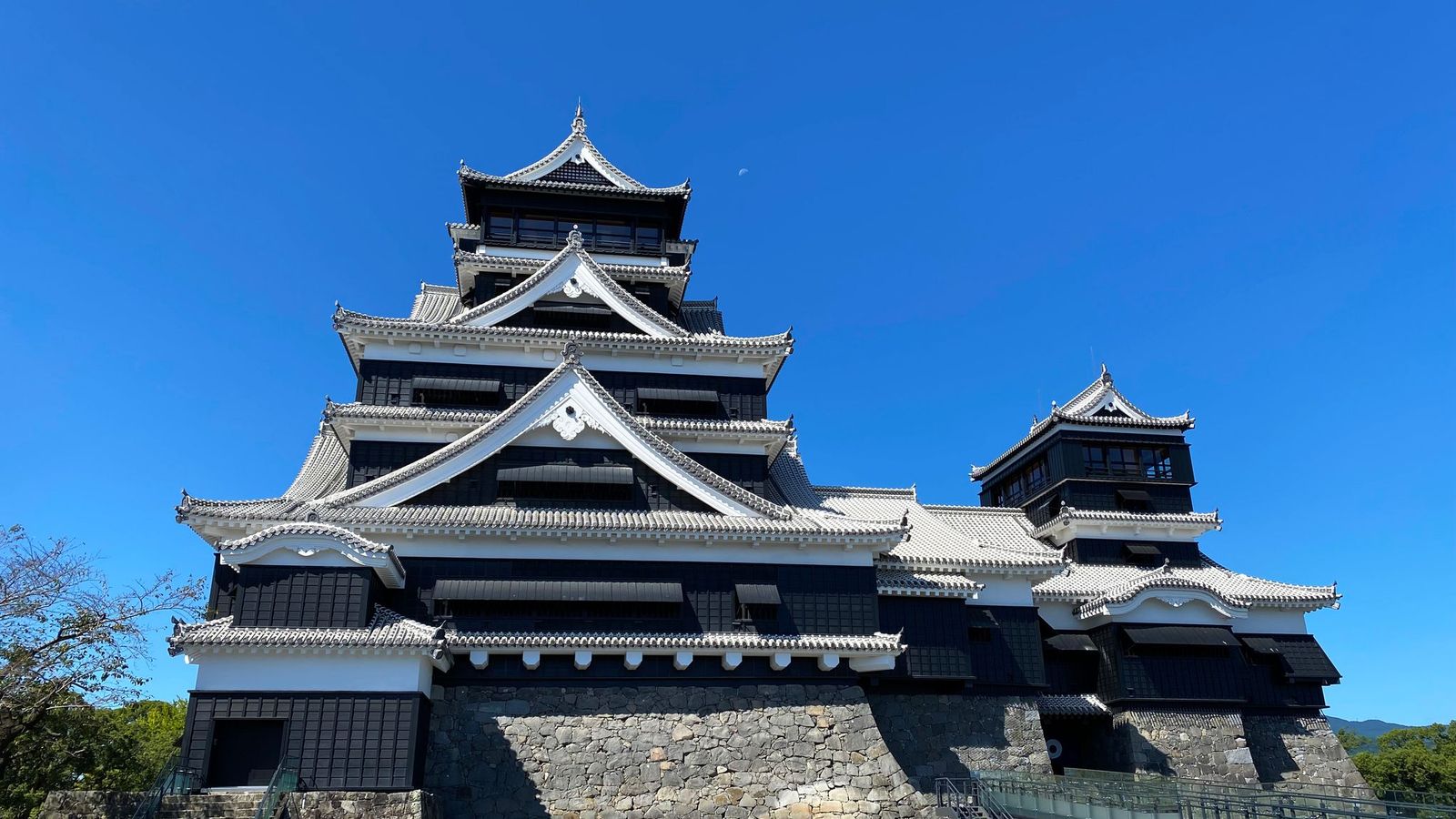 青空の下の熊本城の天守閣と石垣