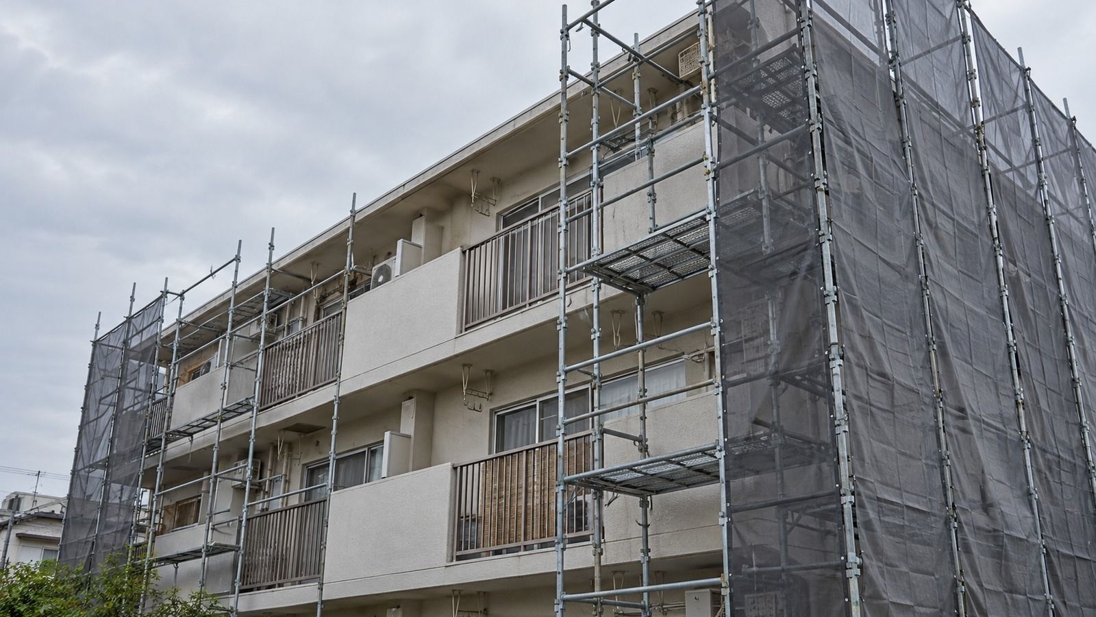 足場とメッシュシートのかかった低層の建物の外壁