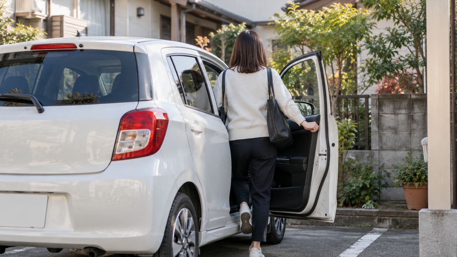 朝の駐車場で車に乗り込む人の後ろ姿