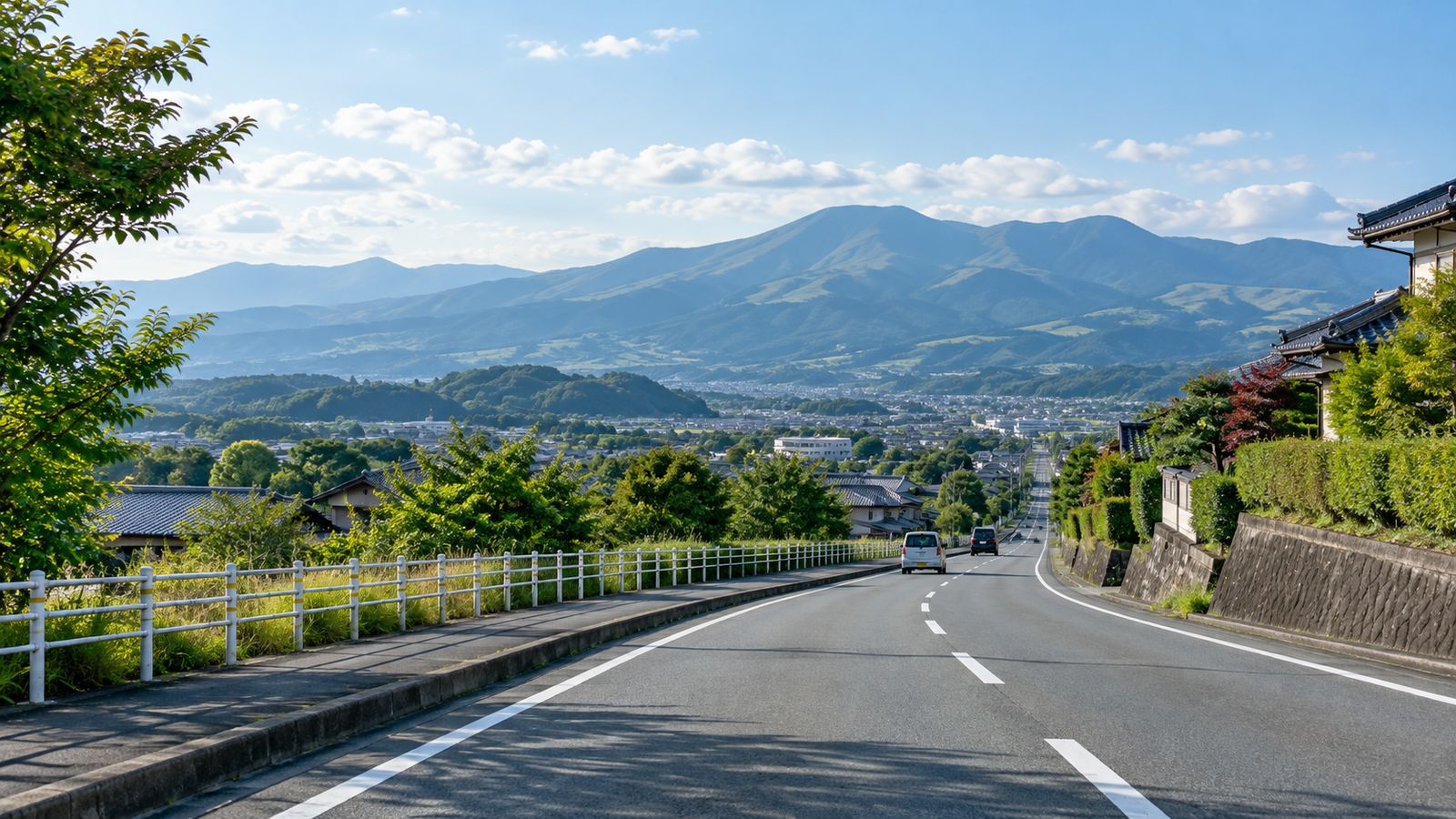 郊外へまっすぐ延びる広い道路と山並み