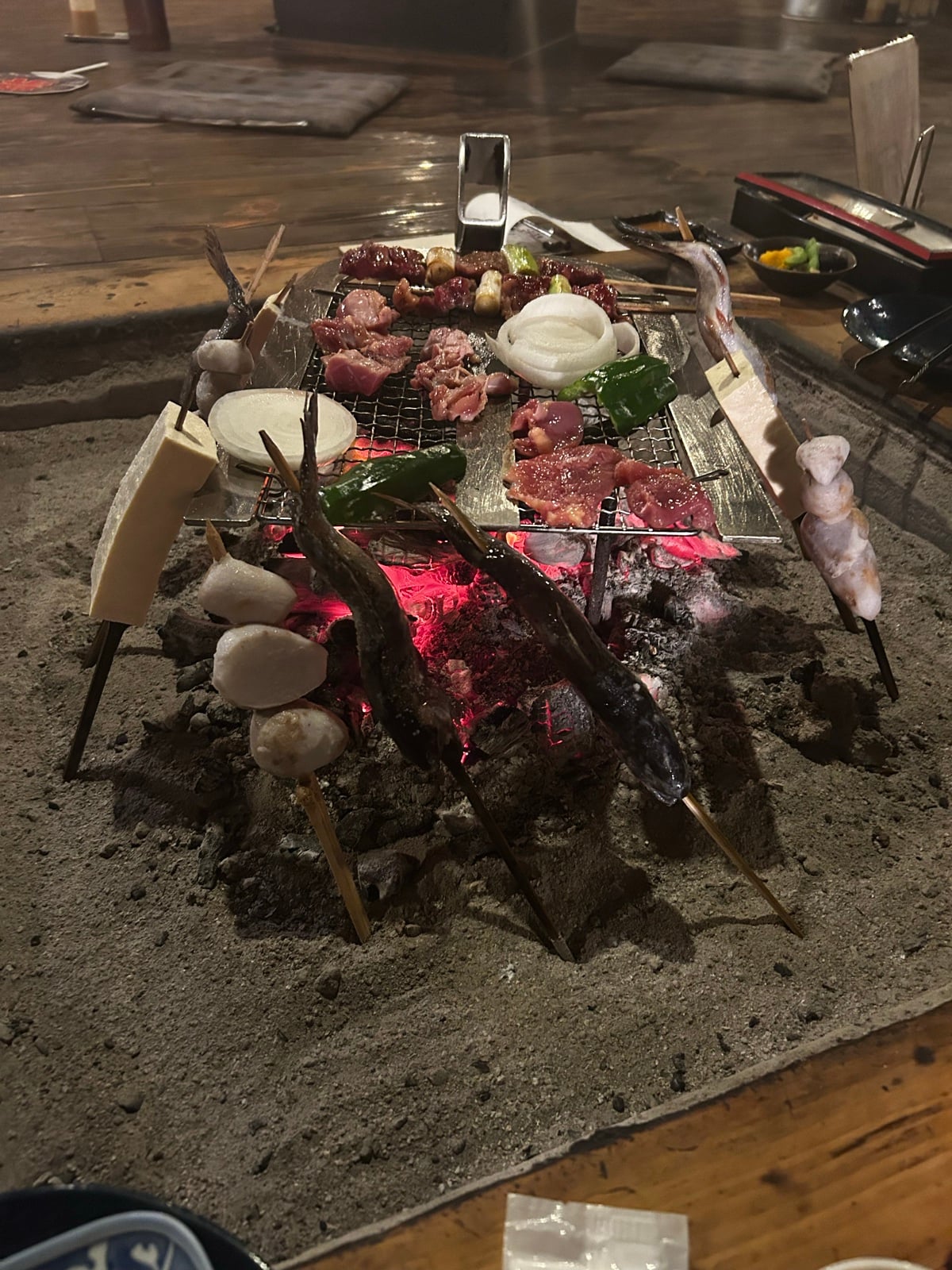 囲炉裏の炭火のまわりに立てて焼く串(2026年7月、編集部撮影)