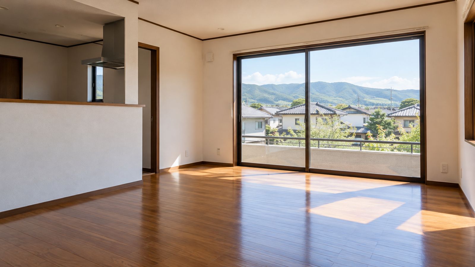 家具のない明るいリビングと窓の外の住宅地と山